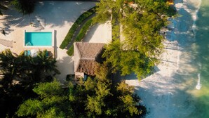 Luchtbeeld van een resort met een zwembad, een overdekt zitgedeelte en weelderige begroeiing.