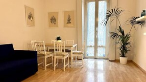 Un comedor con una mesa y sillas de madera, un sofá azul y una planta en maceta.