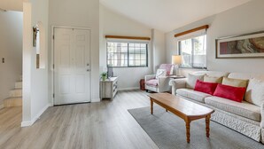 Una sala de estar con sofá, mesa de centro, puerta y ventana.