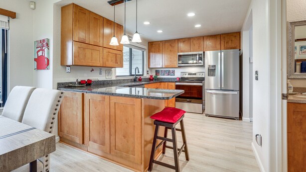 Una cocina moderna con gabinetes de madera, electrodomésticos de acero inoxidable y una isla central con taburetes.