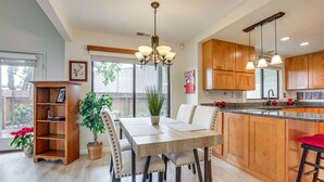 Una cocina moderna con armarios de madera, una mesa de comedor con sillas, una araña y una planta en maceta.