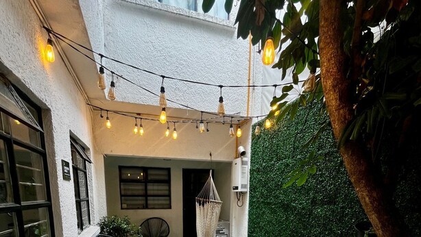 Un patio con luces colgantes, asientos y plantas en macetas.