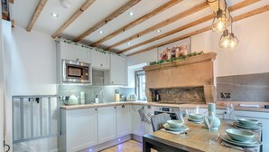 A modern kitchen with wooden beams, a built-in microwave, and a stone fireplace. - 2 bedroom accommodation in Bonsal, near Matlock (Bonsal, near Matlock)