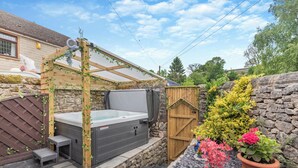 A hot tub with a wooden pergola, stone walls, and potted plants. - 2 bedroom accommodation in Bonsal, near Matlock (Bonsal, near Matlock)