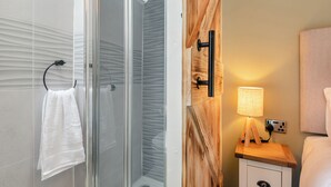 A modern bathroom with a glass shower enclosure, a wooden vanity with a lamp, and a white towel hanging on a rack. - 2 bedroom accommodation in Bonsal, near Matlock (Bonsal, near Matlock)