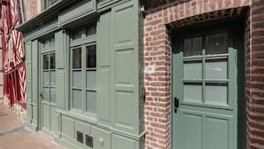 En bygningsfacade med grønne døre og vinduer, murstensvægge og et traditionelt udtryk.