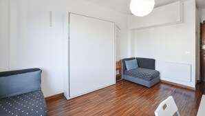 A room with a wooden floor, a grey sofa with a polka dot cover, a small grey armchair, and a white wardrobe. - Stunning apartment in Bordighera (Bordighera)
