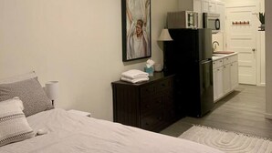 Une chambre à coucher avec un lit, une commode et un tableau accroché au mur.