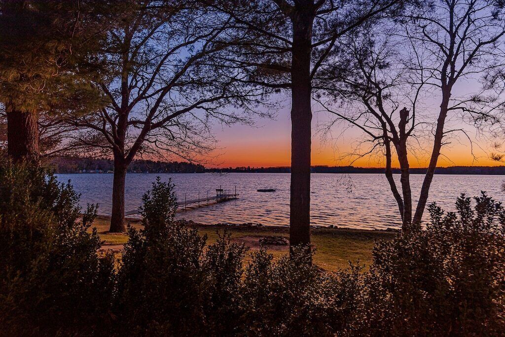 Una vista tranquila de un lago rodeado de árboles y un muelle.