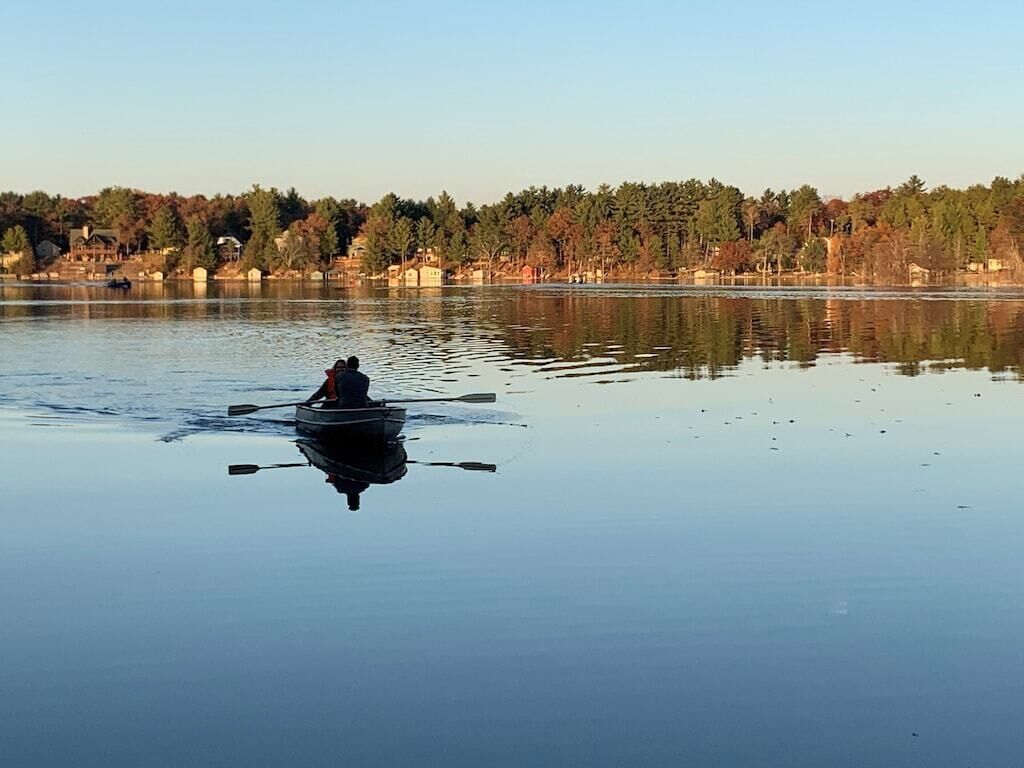 Un lac paisible, avec une seule barque à rames et une personne qui rame.