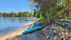 A lakeside scene with a sandy beach, a row of boats, and a wooden fence. - Cozy Cottage with so many amenities, on beautiful Little Hills Lake in Wautoma (Wautoma)