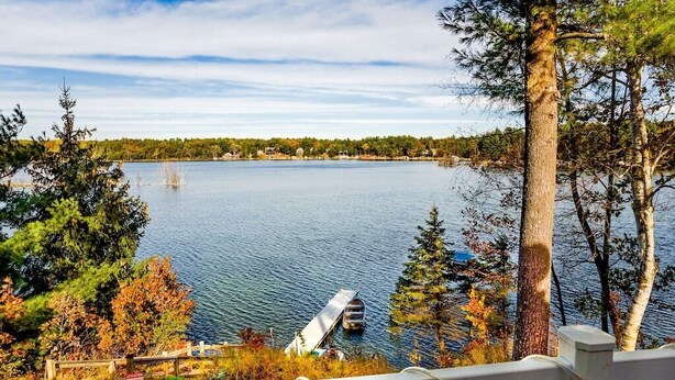 A lake with a dock extending into the water, surrounded by trees and a distant shoreline. - Cozy Cottage with so many amenities, on beautiful Little Hills Lake in Wautoma (Wautoma)