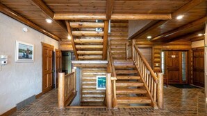 Un escalier en bois, avec un motif de plancher en chevrons, menant aux niveaux supérieurs.