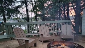 A deck with Adirondack chairs and a fire pit. - Amazing view, hot tub, sauna, fireplace, pet friendly, pier, kayaks, paddleboard (Wautoma)