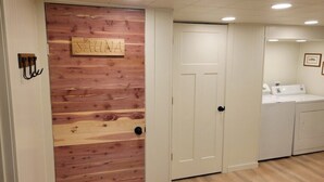 A room with a wooden wall, a white door, a white wardrobe, and a washing machine. - Amazing view, hot tub, sauna, fireplace, pet friendly, pier, kayaks, paddleboard (Wautoma)