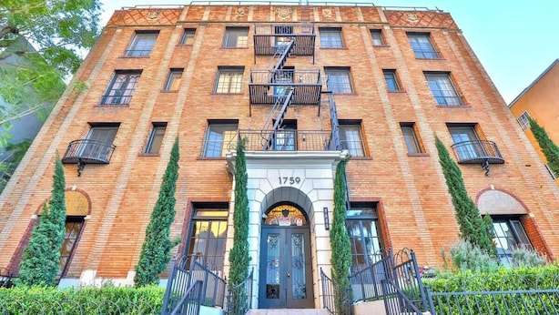 A multi-story brick building with a central entrance, fire escape, and numbered address 1759. - Furnished Bachelor in Hollywood (Los Angeles)