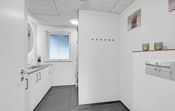 Un couloir étroit avec une porte blanche, une fenêtre à vitres dépolies et une petite plante en pot.
