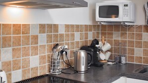 Een keuken met een fornuis, magnetron en diverse keukengerei.