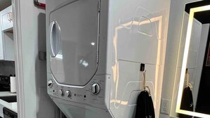 A compact, modern bathroom with a built-in washing machine, a sink, and a mirror.
