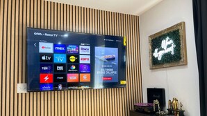 A flat-screen TV mounted on a wall with a wooden panel design.