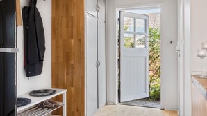 A hallway with a wooden floor, a white door leading outside, and a shoe rack with slippers. - 3 bedroom gorgeous home in Børkop (Børkop)
