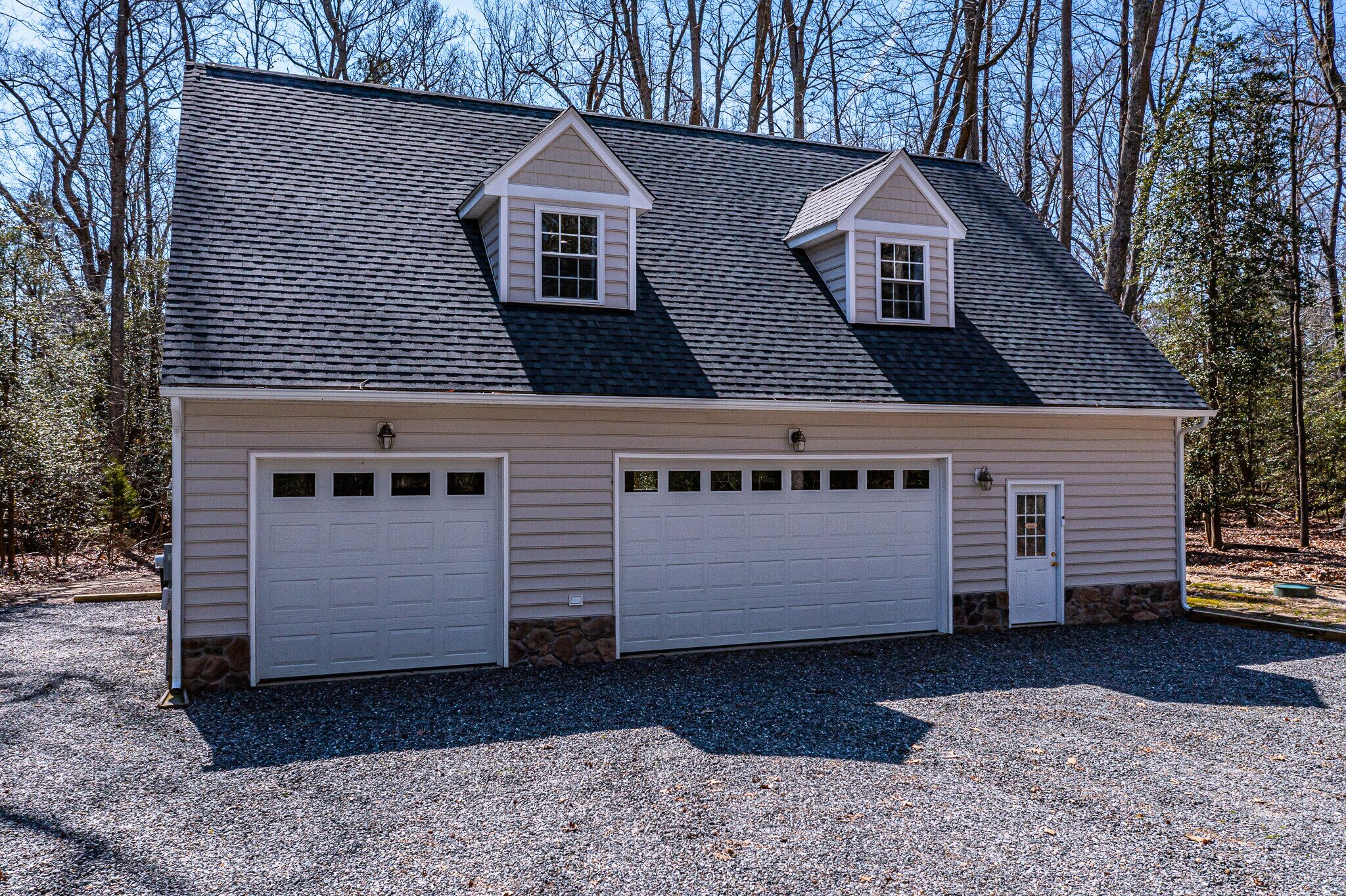 A two-story house with a garage, a small attic window, and a stone foundation.