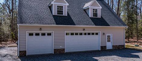 A two-story house with a garage, a small attic window, and a stone foundation.