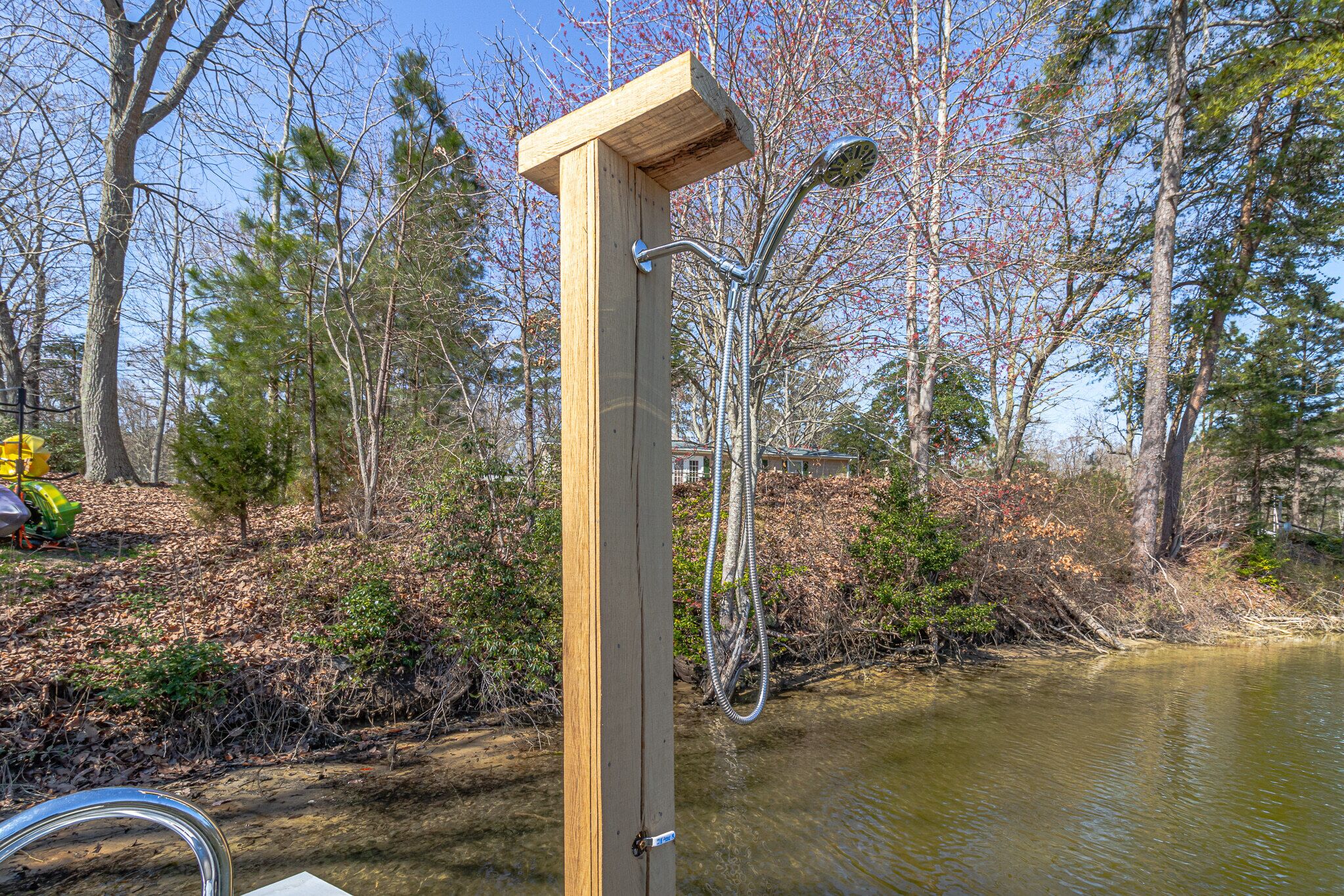Een houten constructie met een douchekop, omgeven door bomen en water.
