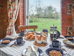 Mesa de café da manhã com croissants, ovos, cereais e utensílios para café.
