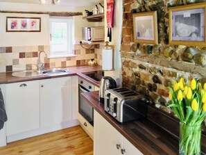 Une cuisine avec un mur en pierre, un plan de travail en bois et un grille-pain.