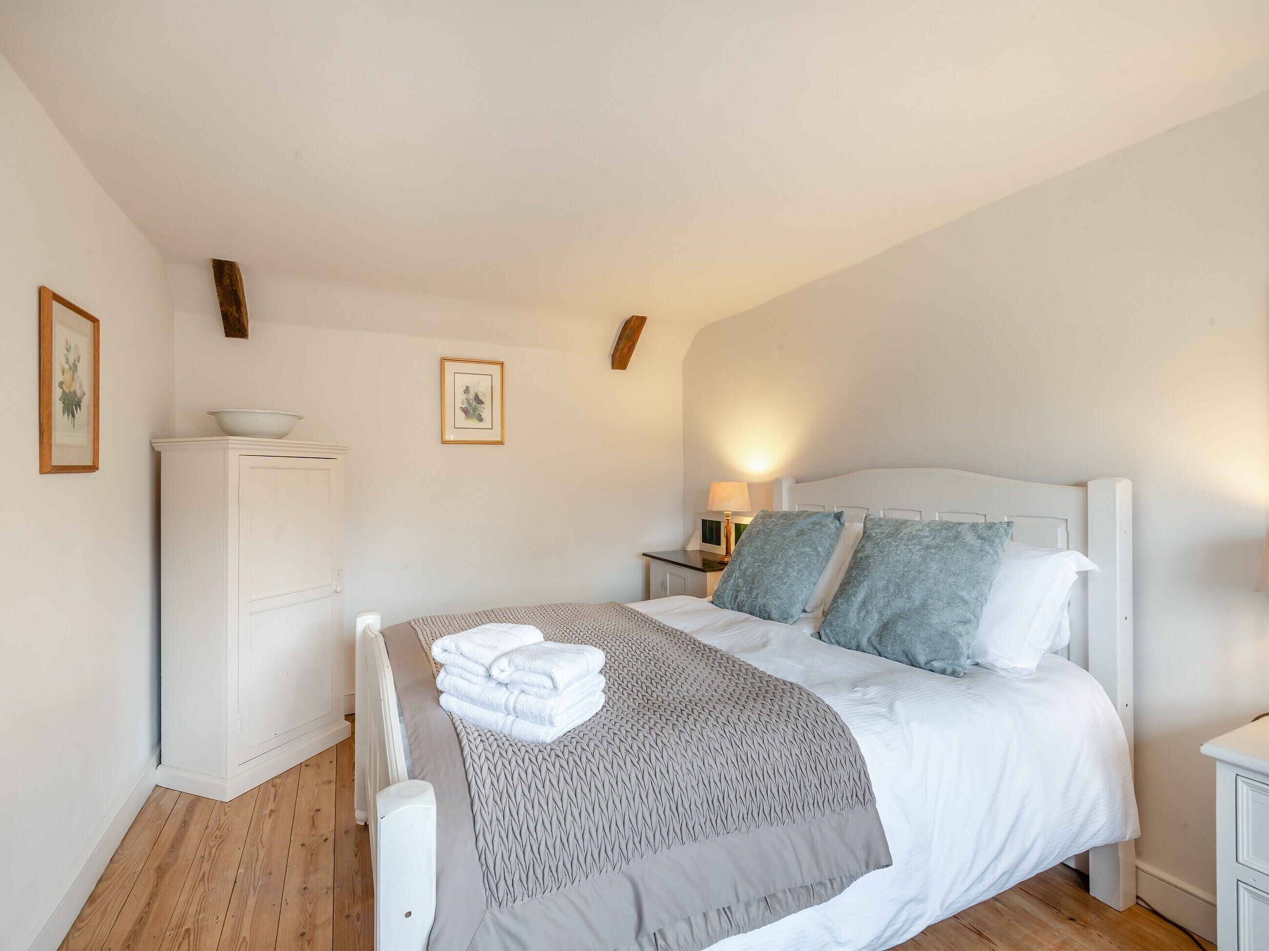 A neatly arranged bedroom with a bed, bedside tables, and a wardrobe.