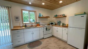 A compact kitchen with white cabinets, a wooden ceiling, and a window providing natural light. - Cottage 2/Roaring River/TRL/EurekaSprings/Wi-Fi (Eagle Rock)