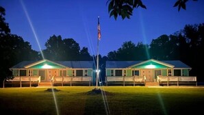 Dois edifícios de motel com um mastro de bandeira no meio, rodeados por árvores.