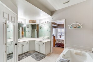 Un baño con un espejo grande, tocador y bañera.