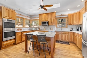 A spacious kitchen with wooden cabinets, stainless steel appliances, and a large island with bar stools. - Family-Friendly 4BR Home w/ Views – Minutes to Town (Estes Park)