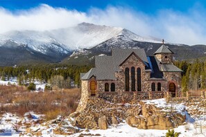 A stone church with a bell tower, set against a backdrop of snow-covered mountains and a clear sky. - Family-Friendly 4BR Home w/ Views – Minutes to Town (Estes Park)