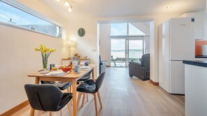 A modern kitchen with a dining area, large windows, and a view of the sea. - 2 bedroom accommodation in Lochranza (Lochranza)