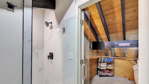Une salle de bain moderne avec une douche à l’italienne en verre, des carreaux de marbre et un plafond en bois.