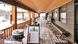 Un espace extérieur abrité, doté d’un plafond en bois et d’une enseigne indiquant « Pizzanos Pizzeria ».