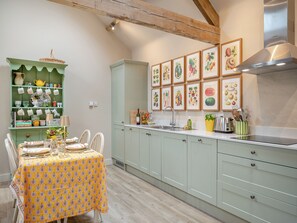 A kitchen with a dining table set, a green cabinet with kitchenware, and framed botanical illustrations on the wall. - 2 bedroom accommodation in Appletree (Appletree)
