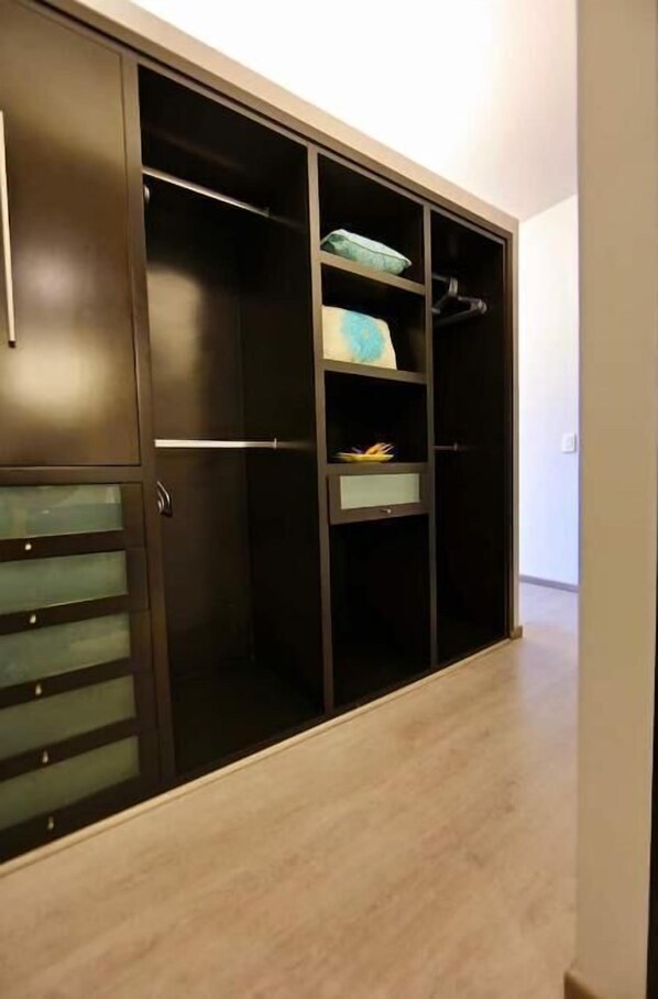 A walk-in closet with multiple shelves and drawers, a hanging rod, and a mirrored section.