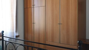 Une armoire en bois à deux portes, dotée d’une poignée, d’une tringle en métal et d’une fenêtre avec un rideau.
