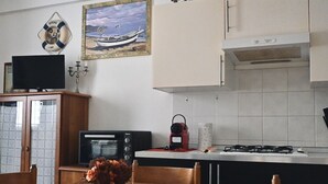 Une cuisine équipée d’une cuisinière, d’un four et d’un téléviseur posé sur un meuble.