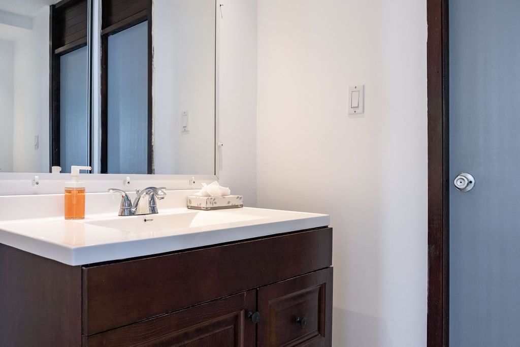 A bathroom with a white sink, dark wooden vanity, and a large mirror.