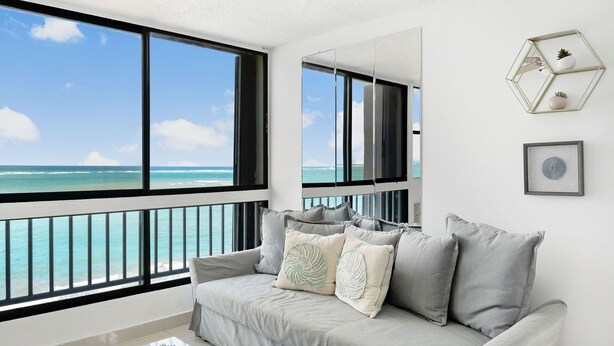 Un salón moderno con un ventanal grande con vistas a la playa.