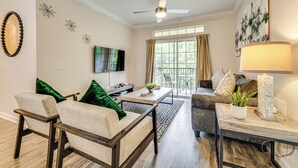 A modern living room with a sofa, chairs, a coffee table, and a TV. - 10 Mi to Disney! Resort Condo at ChampionsGate (Davenport)