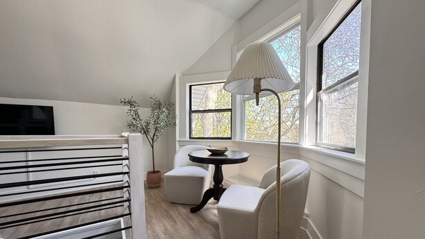 A modern room with a white crib, a round table with chairs, and a floor lamp.