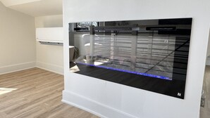 A modern room with a large black-framed window, a white wall, and a wooden floor.