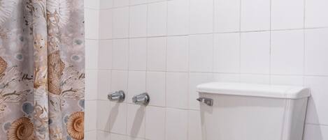 Un baño con inodoro, ducha y cortina decorada con motivos florales.