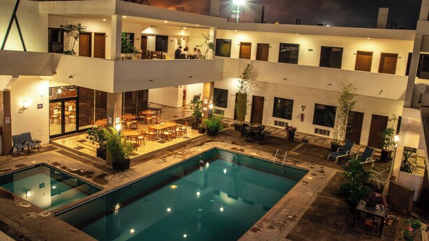 Ein mehrstöckiges Hotel mit Schwimmbad, Außenbereich zum Sitzen und mehreren Balkonen.